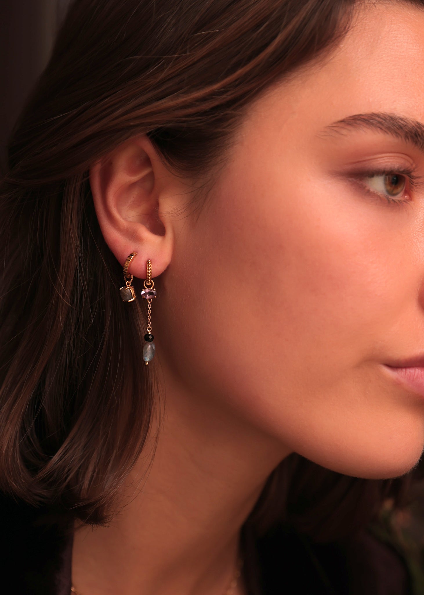 Kvinde med lange hængeøreringe i guld med ametyst, spinel og labradorit ædelsten fra carré jewellery 