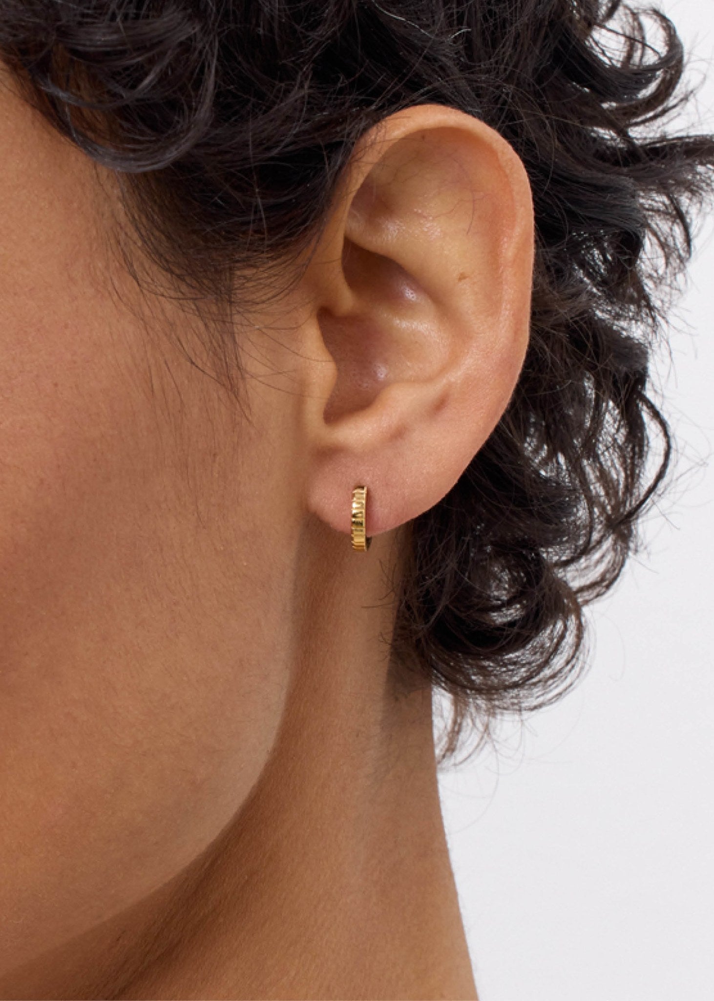 Kvinde med lille huggie hoop i guld fra carré jewellery på udsalg med små nålestriber i dansk design 