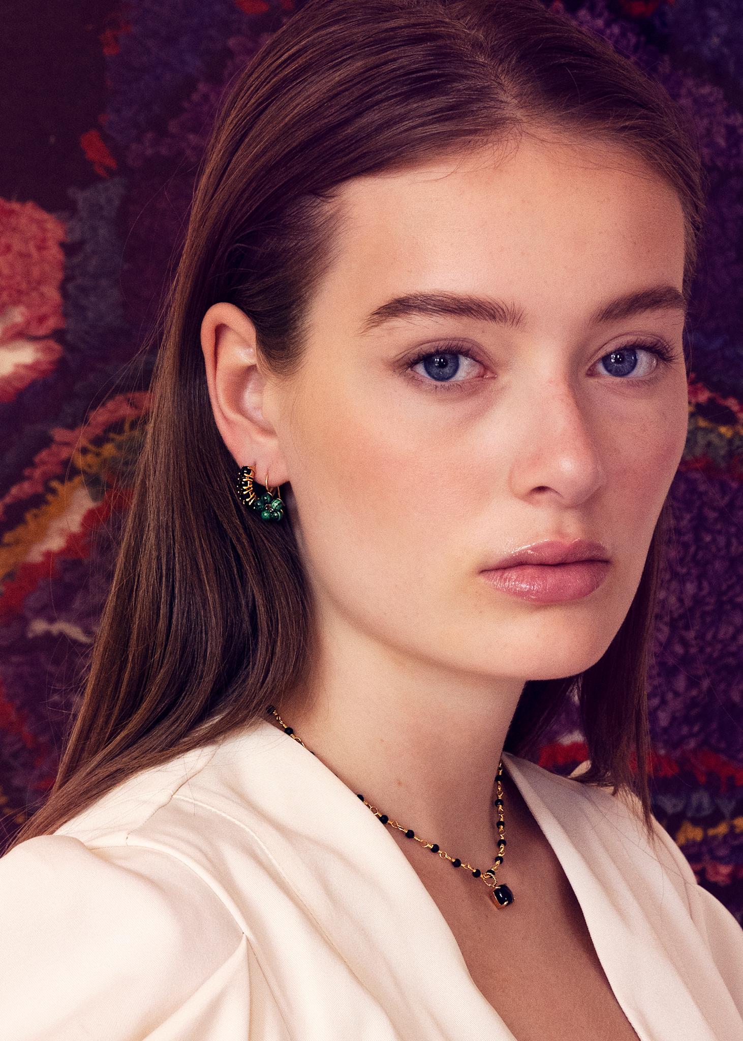 Ung kvinde med store hoops i guld med sorte ædelsten