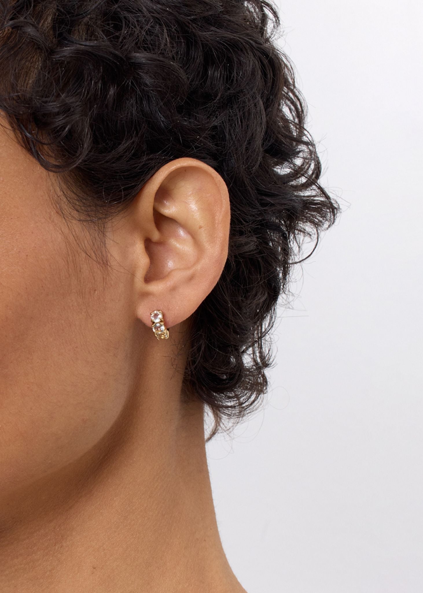 Kvinde med gem huggie hoops fra carré jewellery i guldbelagt sterling sølv med tre facetslebne prasiolit ædelsten i lysegrønne nuancer på udsalg lige nu 