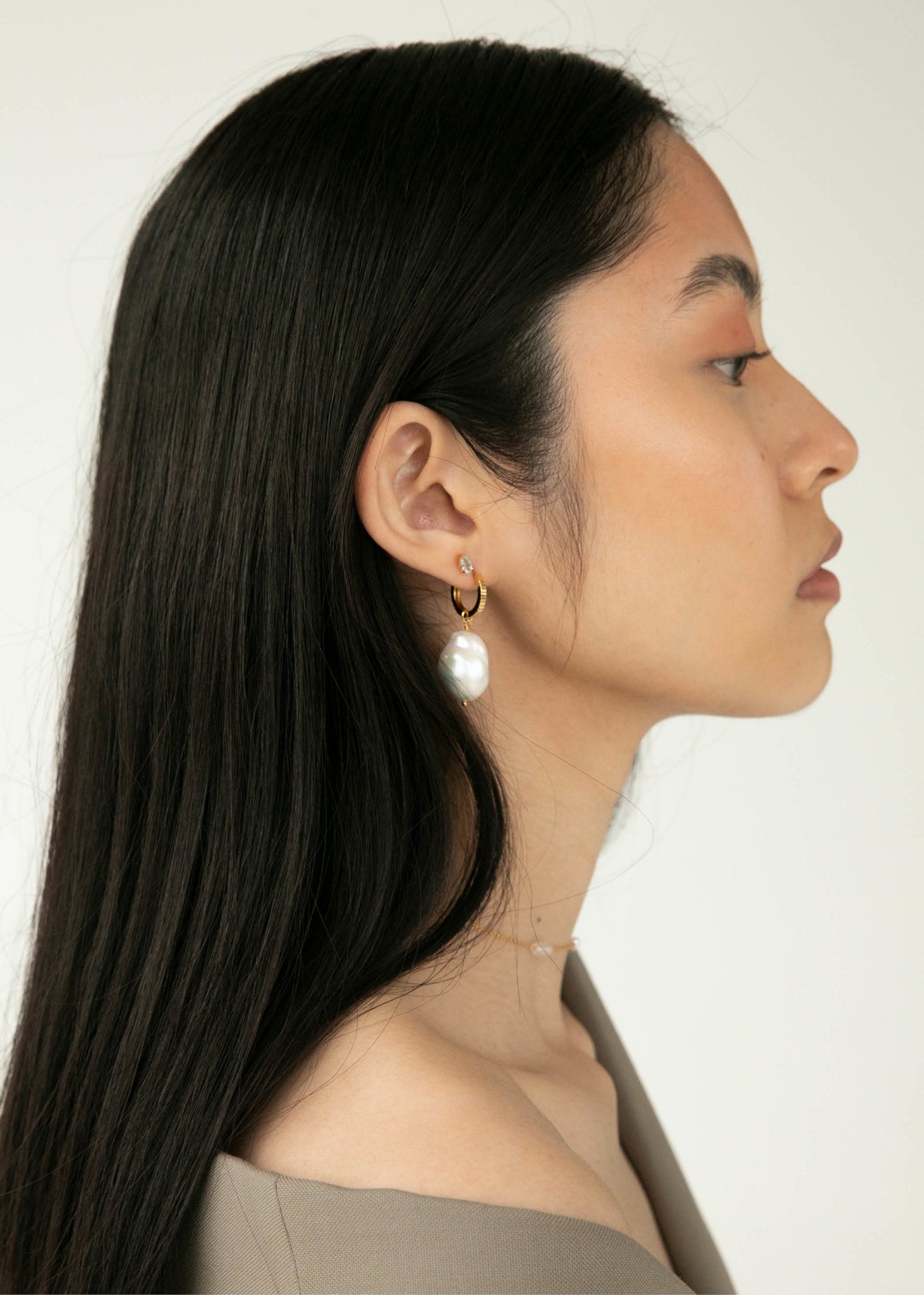 Kvinde med perleøreringe fra carré jewellery med en stor barok ferskvandsperle i guld til mænd og kvinder 