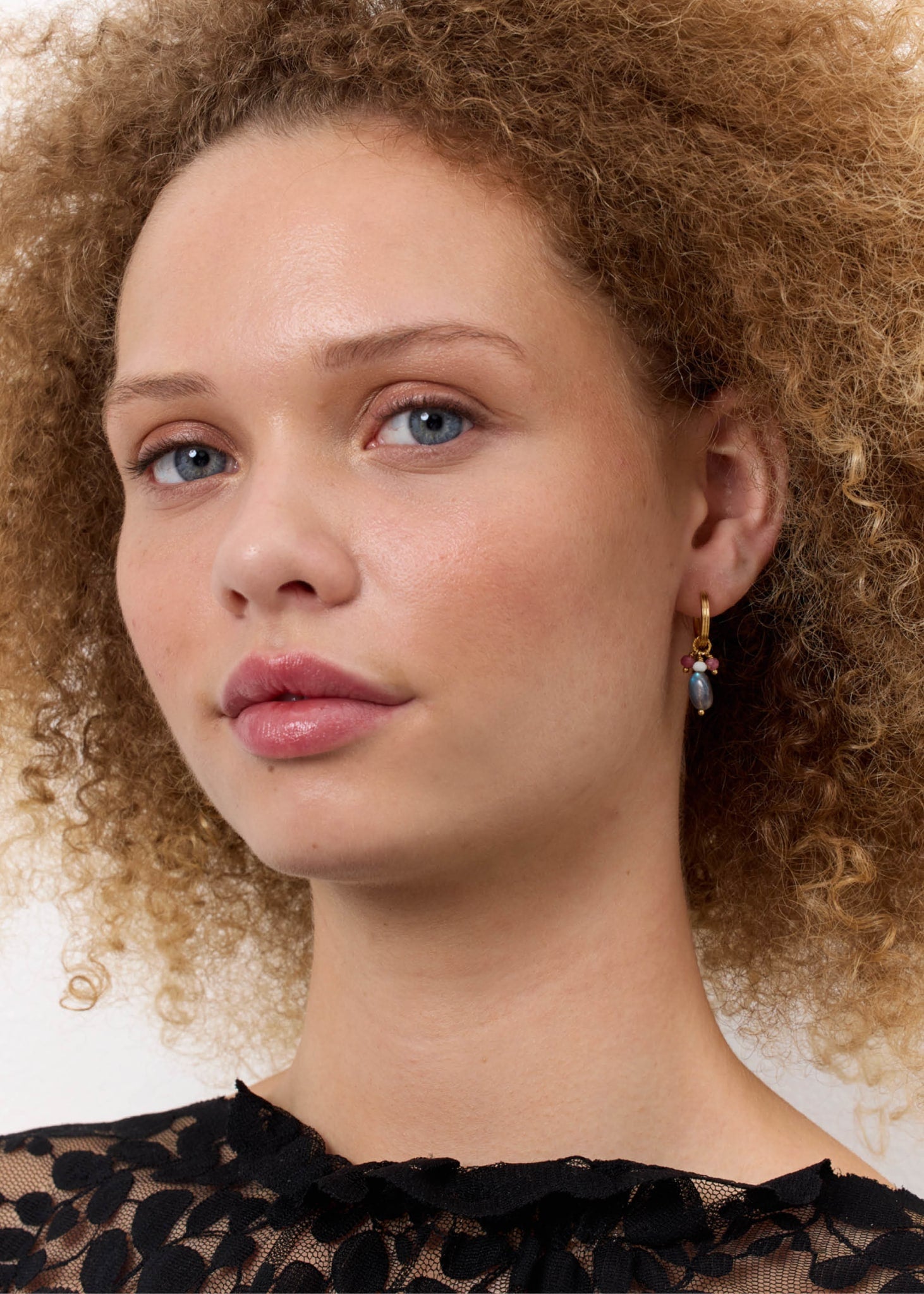 kvinde med dinglende øreringe fra carré Jewellery i guld sat med lyserøde, grønne og labradorit ædelsten