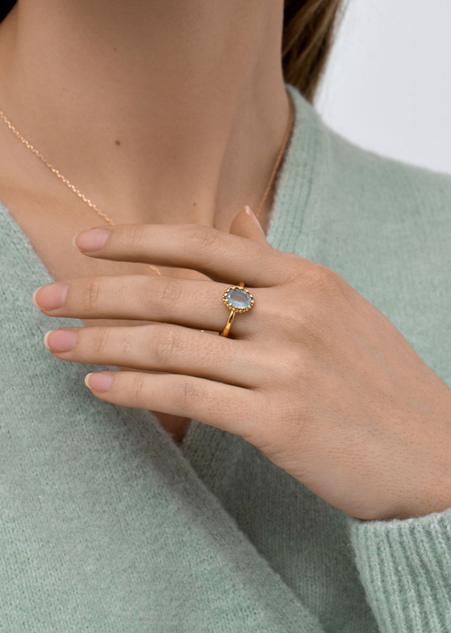 Ung kvinde med guldbelagt ring fra carré jewellery med en blå topas ædelsten i blondefatning