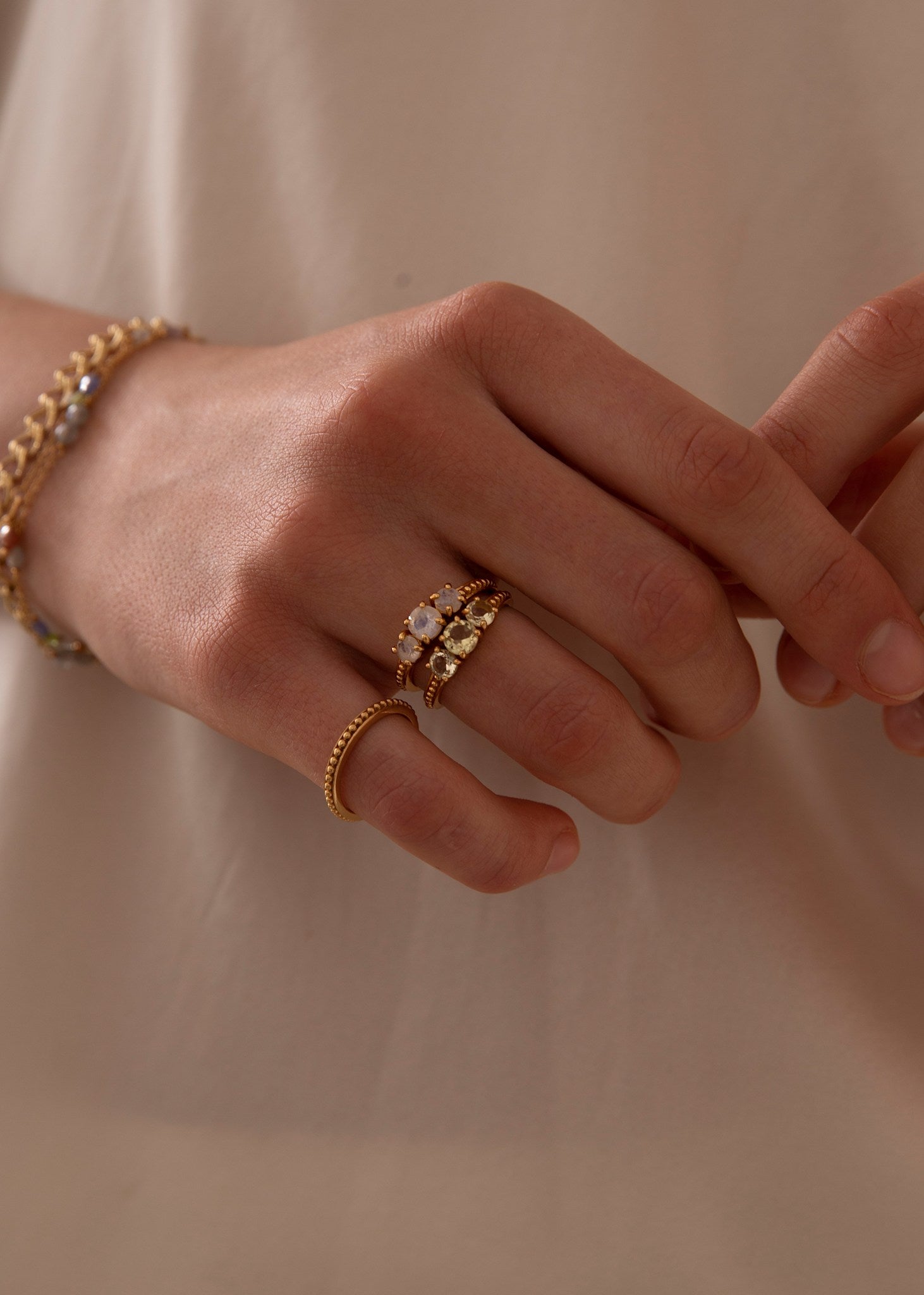 Kvinde med to ringe i guld fra carré jewellery med grønne sten og månesten ædelsten i sterling sølv på tilbud