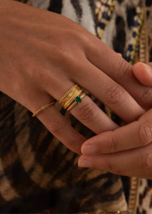 Kvinde med stor guld ring med mønster til mænd og kvinder og en ring med grøn sten fra carré