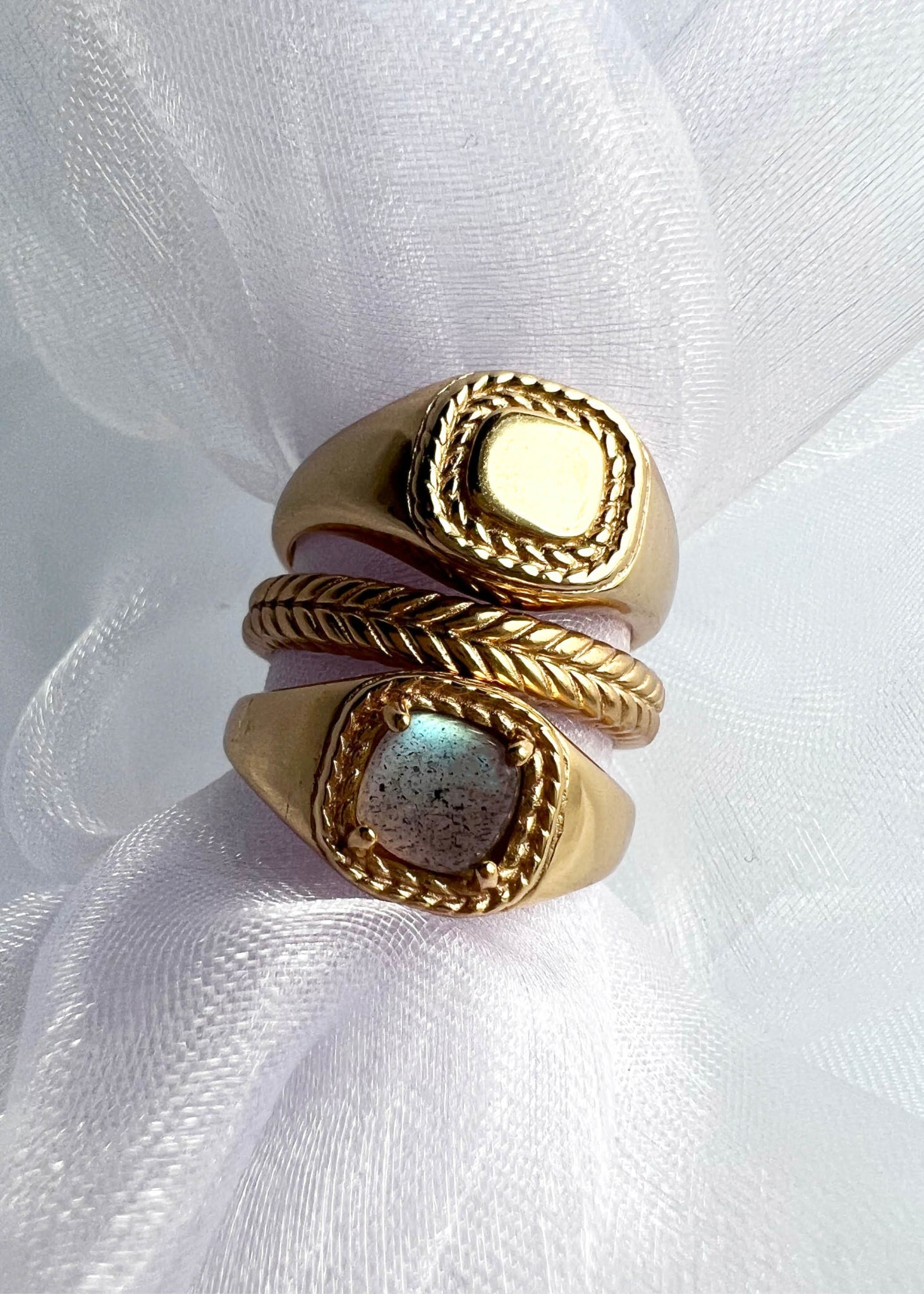 Tre ringe fra carré jewellerys mirage kollektion med sildebensmønster og signét ringe med labradorit ædelsten på silke