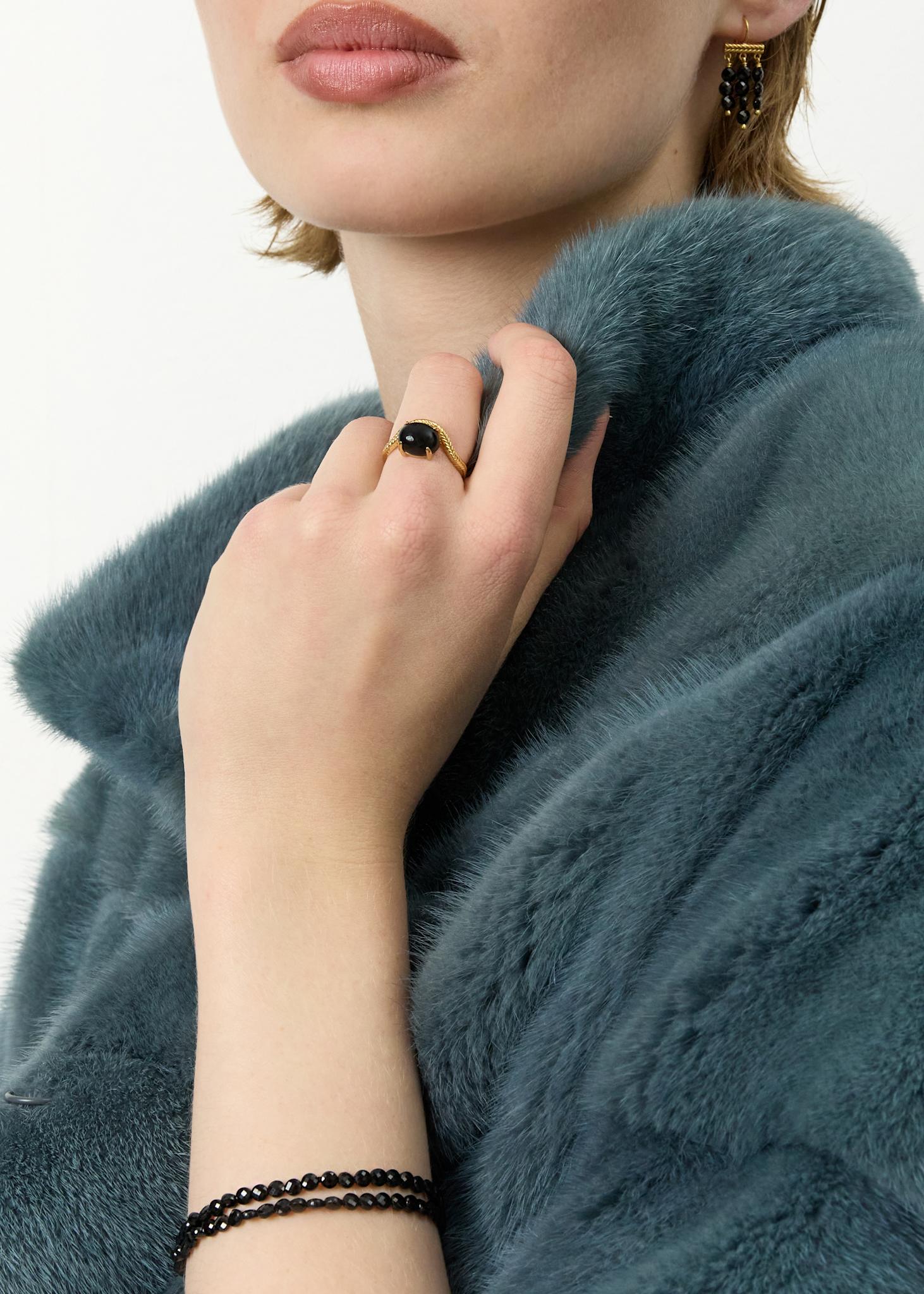 Ung kvinde med elegant ring i guldbelagt sterling sølv med organisk bugtet ringskinne og en cabochonslebet sort agat ædelsten