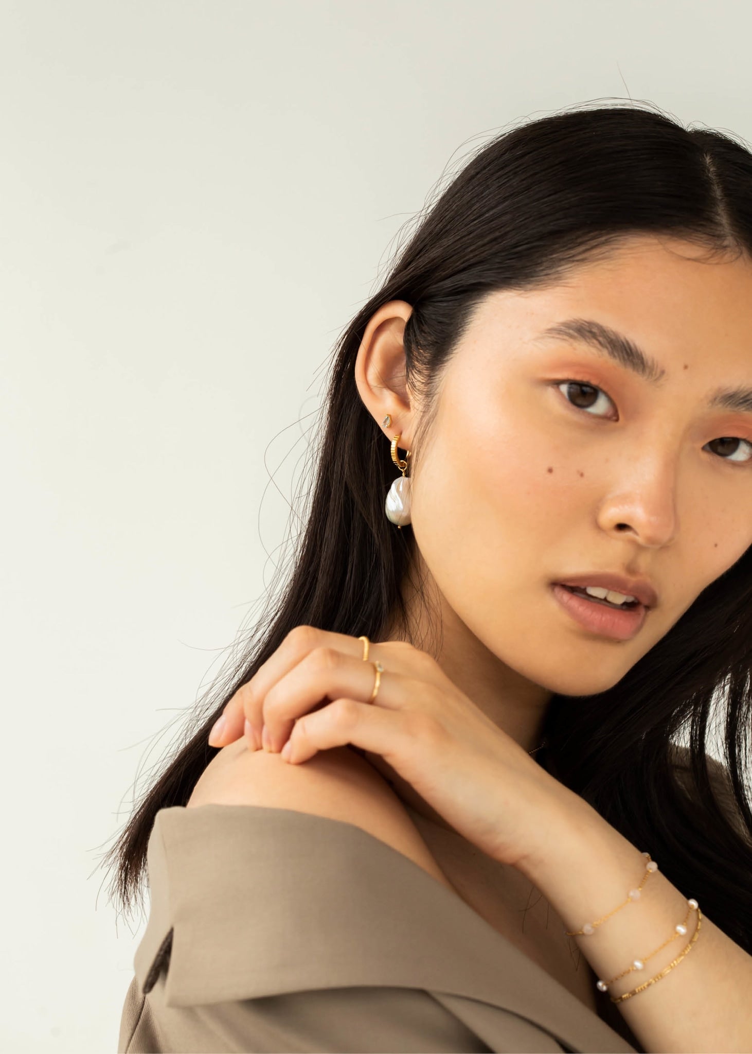 Ung kvinde med lille øre sticker fra carré jewellery i guld med blå topas ædelsten og en stor perleørering i guld