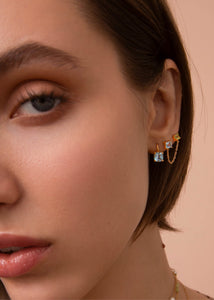 Ung kvinde med guldbelagte øreringe fra carré jewellery med blå topas og grønne peridot ædelsten på udsalg lige nu