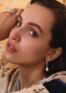 Kvinde med hoops og charms fra carré jewellery i sterling sølv med augusts fødselssten, grøn peridot 