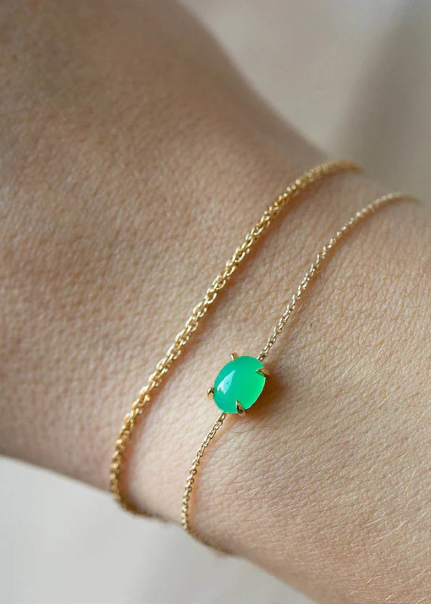 Kvinde med elegante armbånd i ægte guld fra carré jewellery med grønne chrysopras ædelsten på en delikat tynd kæde