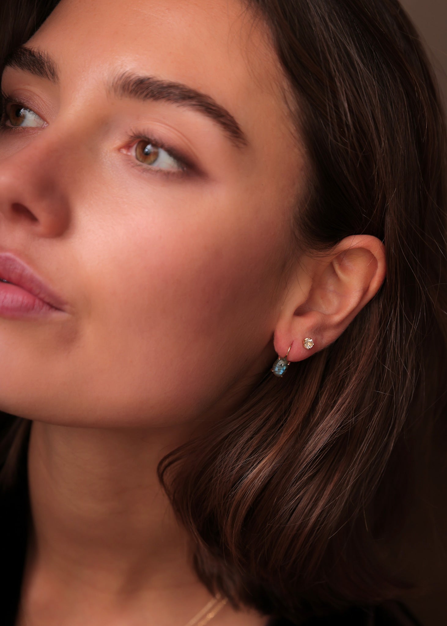 Kvinde med øreringe i ægte 10 karat guld i tournure modellen fra carré jewellery med skinnende labradorit ædelsten 