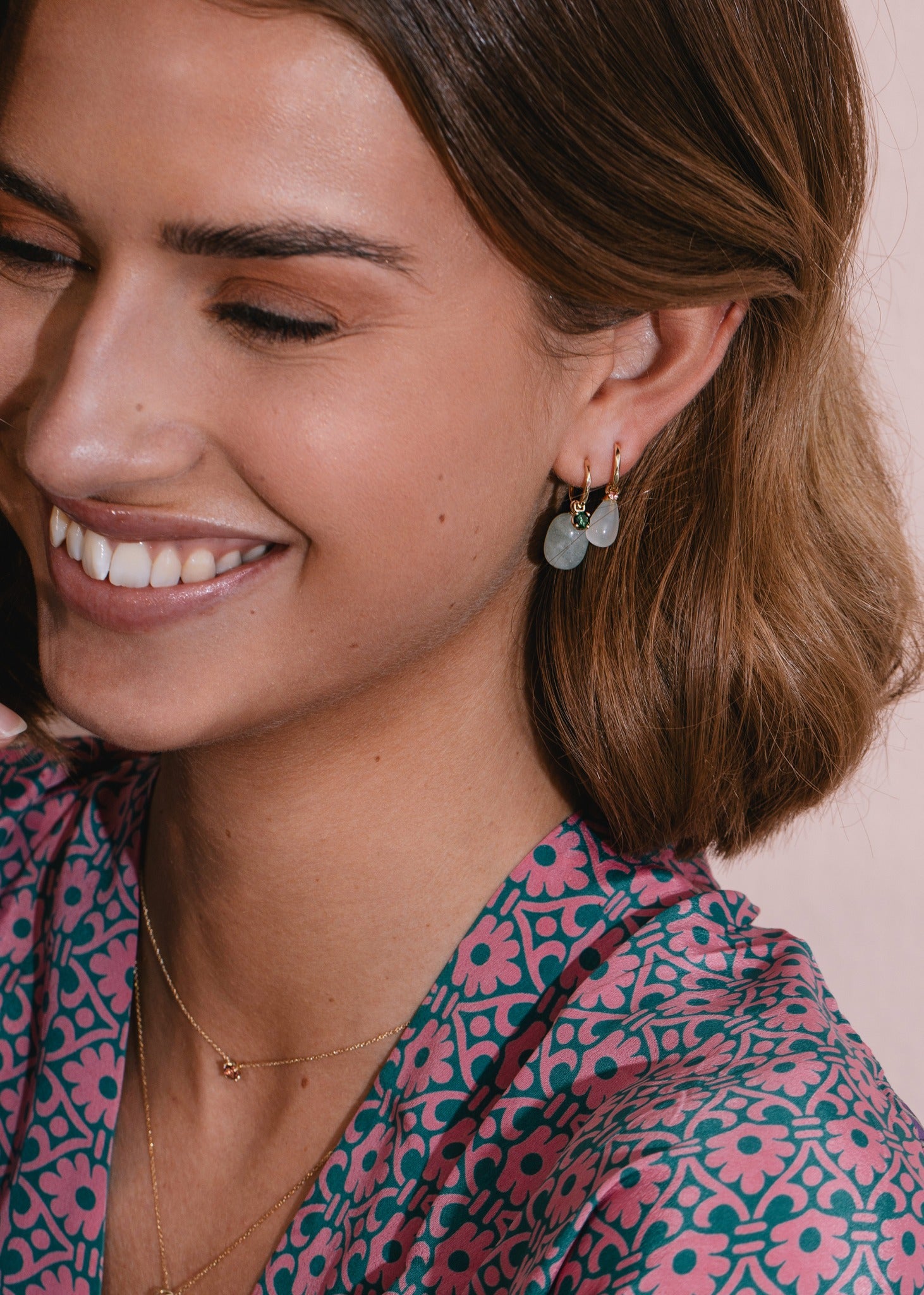 Kvinde med hoops og charms i 10-karat guld fra carré jewellery med grøn turmalin og akvamarin ædelsten