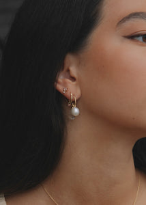 Kvinde med hoops og charms i ægte 10 karat guld fra carré jewellery med ferskvandsperle og lyserøde feminine ædelsten