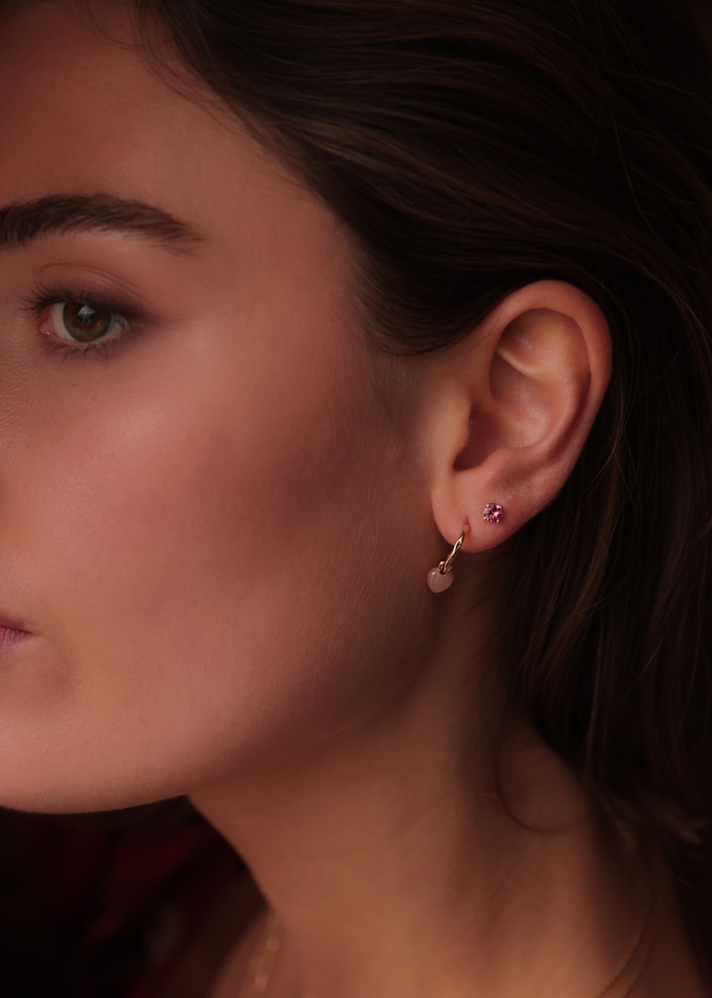 Kvinde med ægte guld øreringe og stikker fra carré jewellery med lyserøde ædelsten
