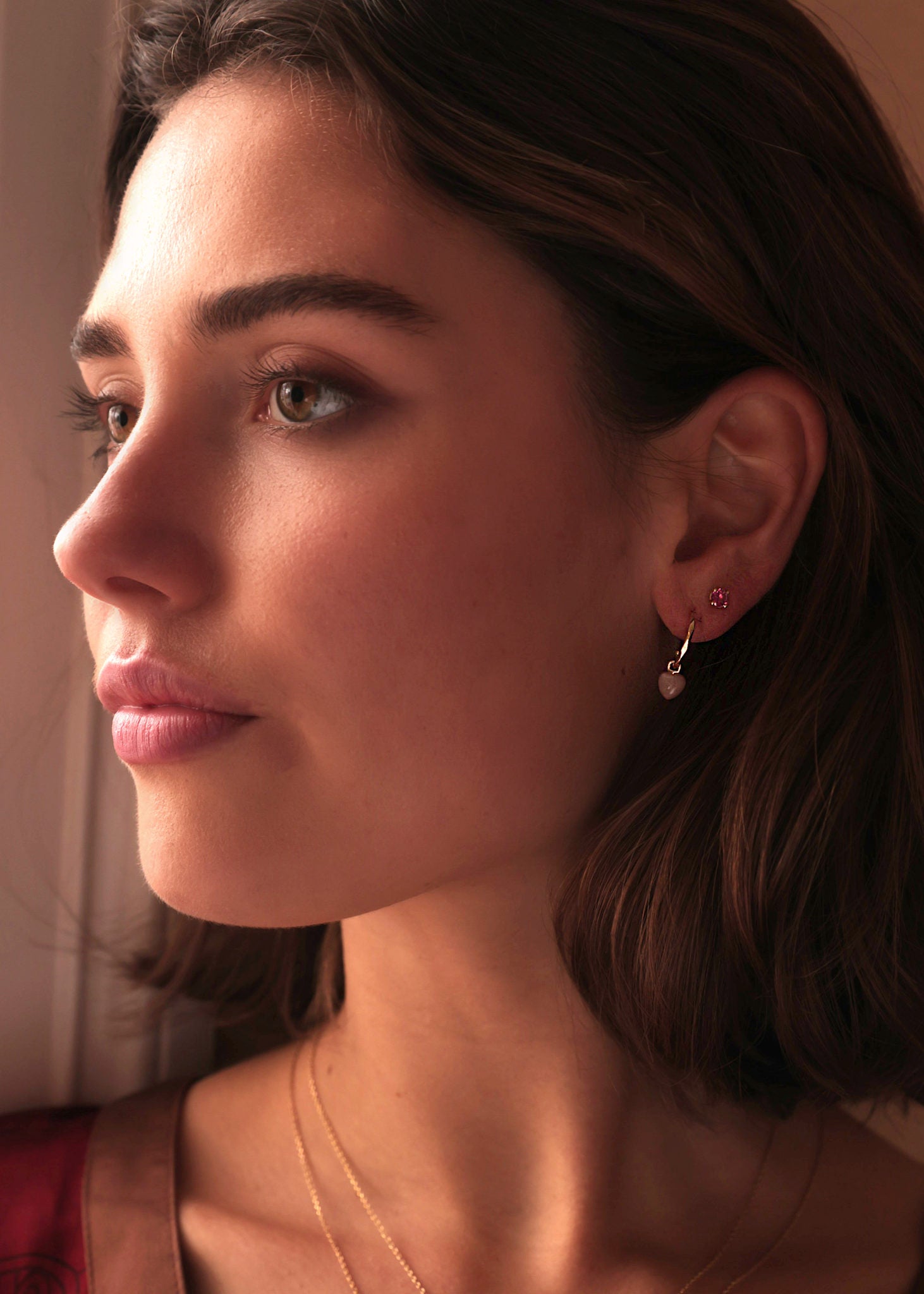 Kvinde med øreringe fra carré jewellery sat med lyserøde hjerteformede månesten ædelsten og en ørestik med lyserød turmalin i guld