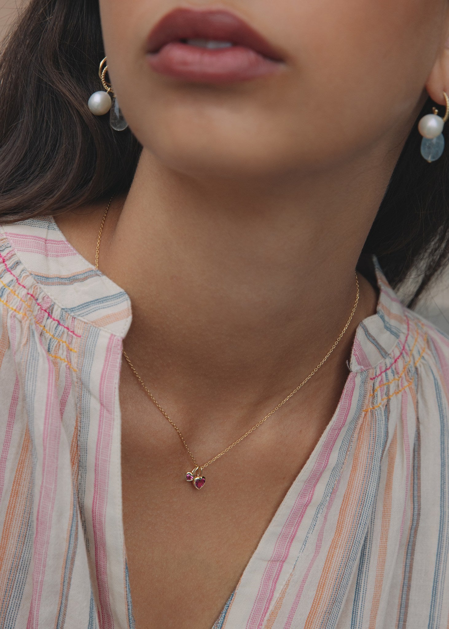 Kvinde med to lyserøde hjertevedhæng til halskæder i ægte 10 karat guld fra carré jewellery med hjerteformede pink turmalin ædelsten