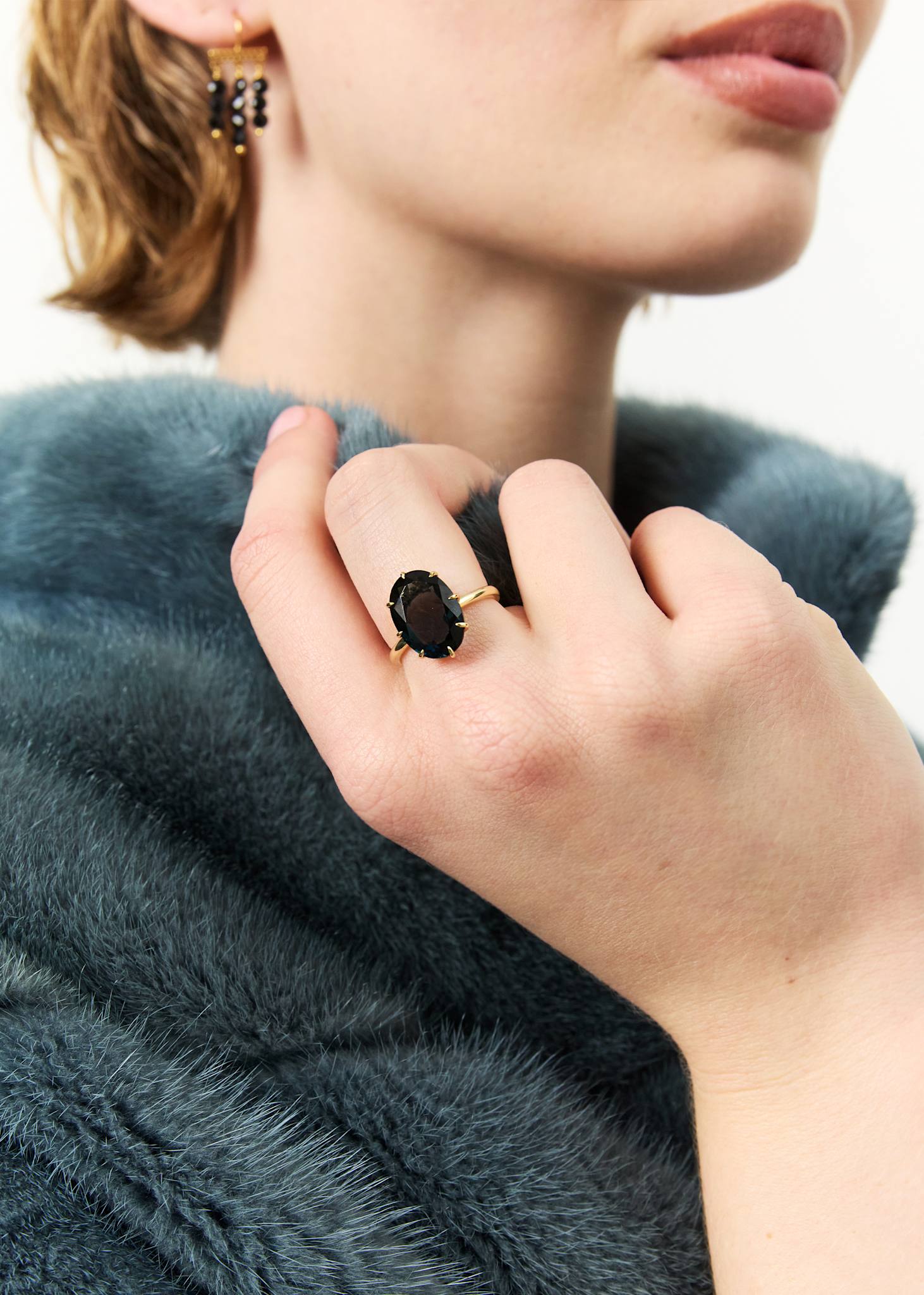 Kvinde med stor cockail ring i 10-karat guld med en ovalsleben London Blå Topas ædelsten i grabbefatninger