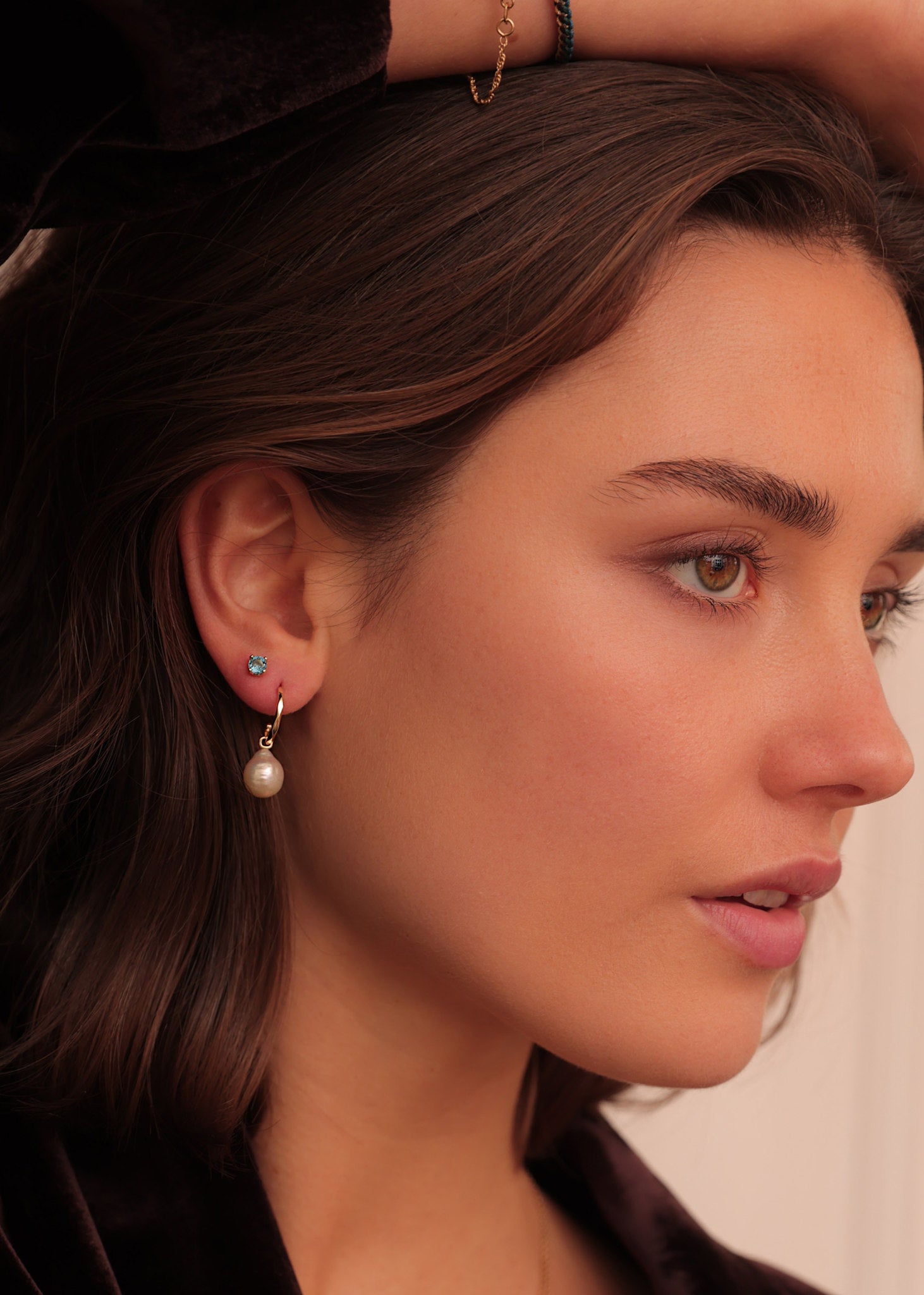 Ung kvinde med smuk lille ørestik i 10 karat ægte guld med novembers fødselssten, london blå topas ædelsten