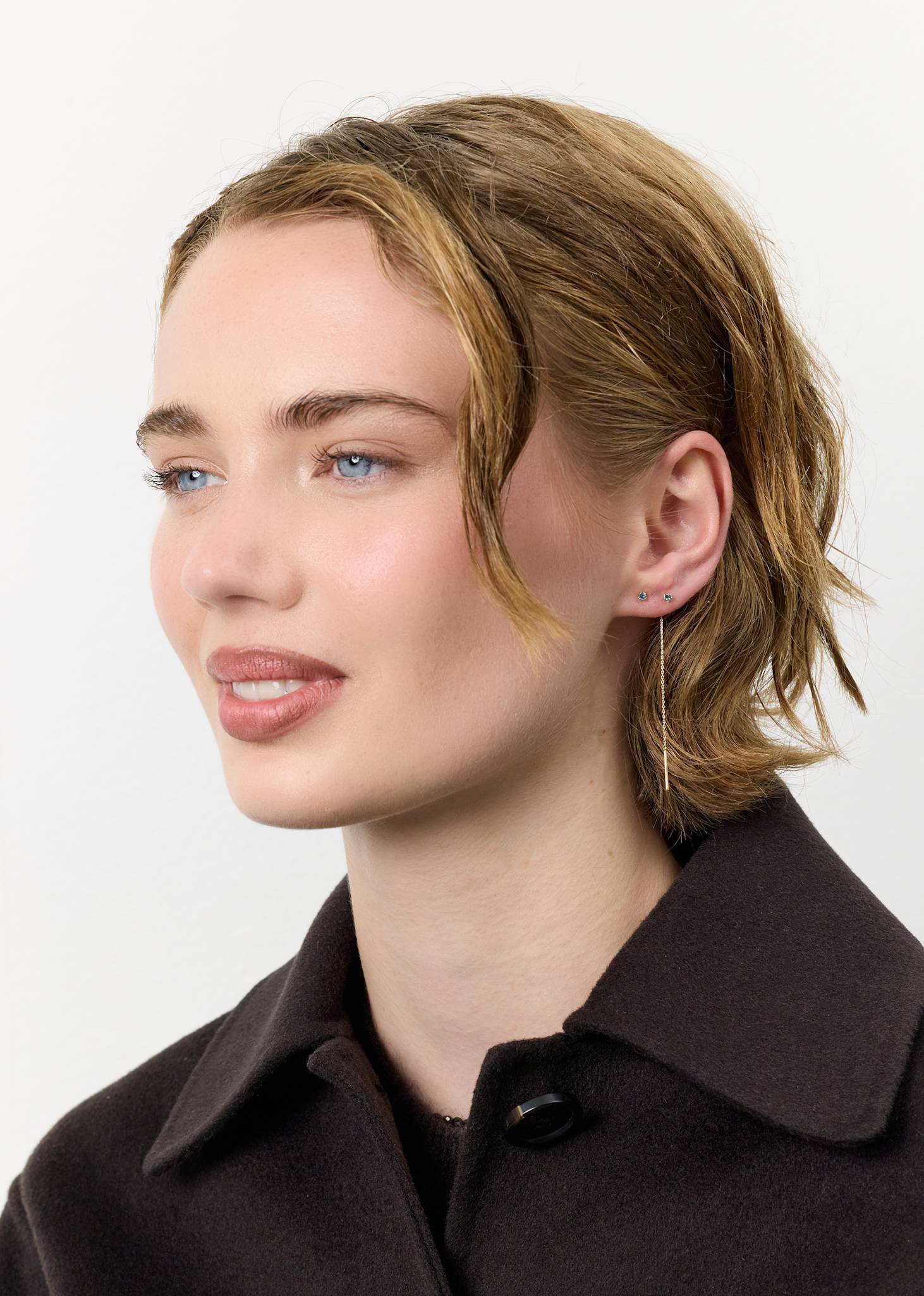 Ung kvinde med smukke ørestikker i 10 karat ægte guld med novembers fødselssten, London Blå Topas ædelsten