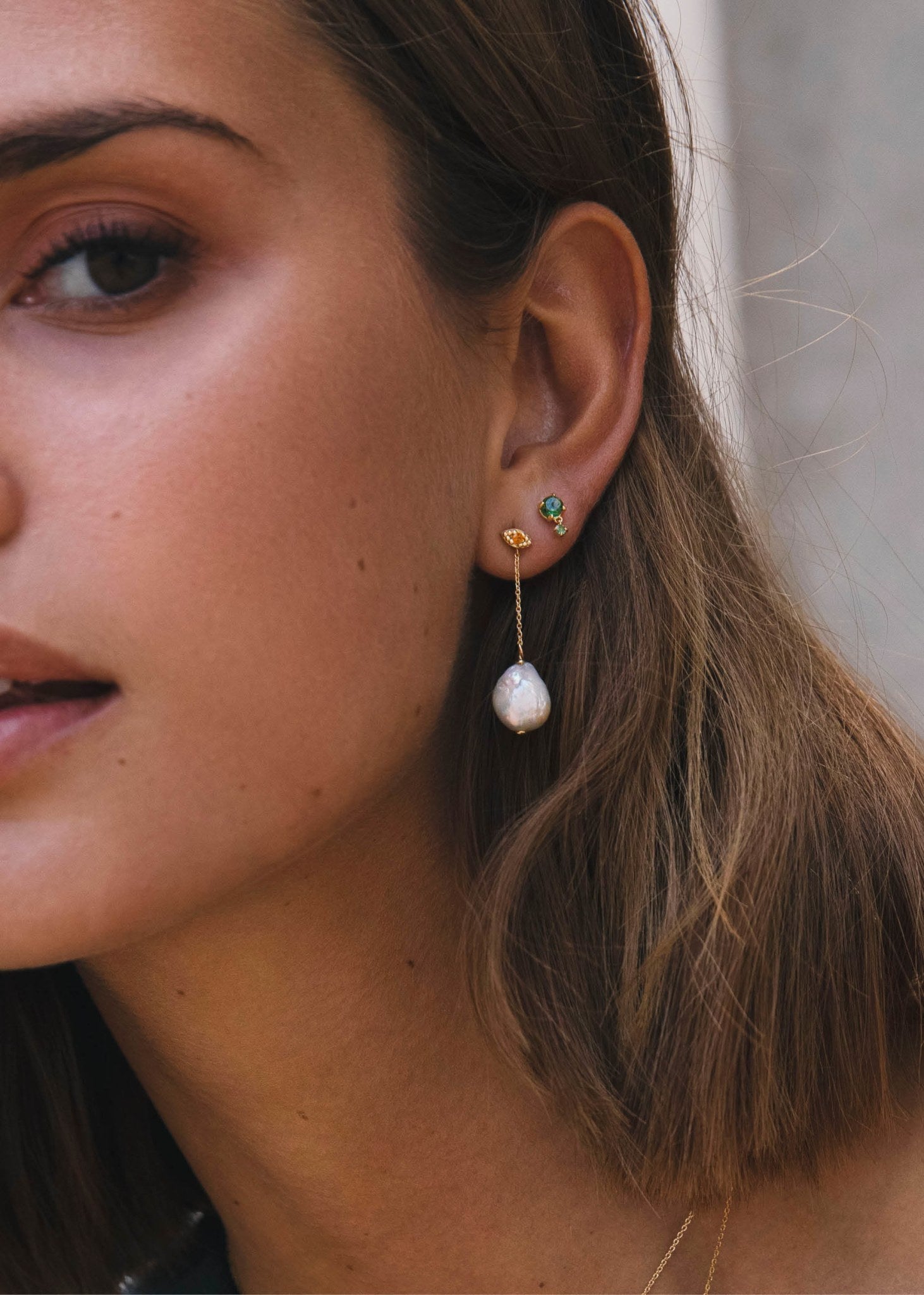 Kvinde der bærer 10 karat guldsmykker fra carré jewellery med en Eye ørestik formet som et øje med en gul ædelsten