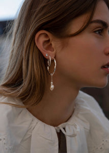 Kvinde med store hoops i sølv med snoet design til mænd og kvinder med et lille ferskvandsperle charm til øreringe