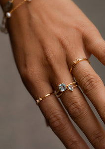kvindehånd med guldbelagte ringe fra Carré. Ringene er sat med Blå topas og er delphine og aqua ringen