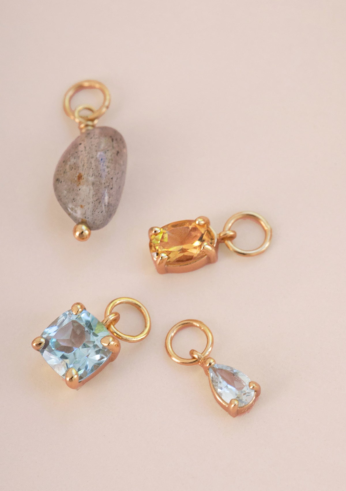 Fire guldbelagte charms fra carré. Charms er sat med en labradorit, en med citrin, og to charms med blå topas.