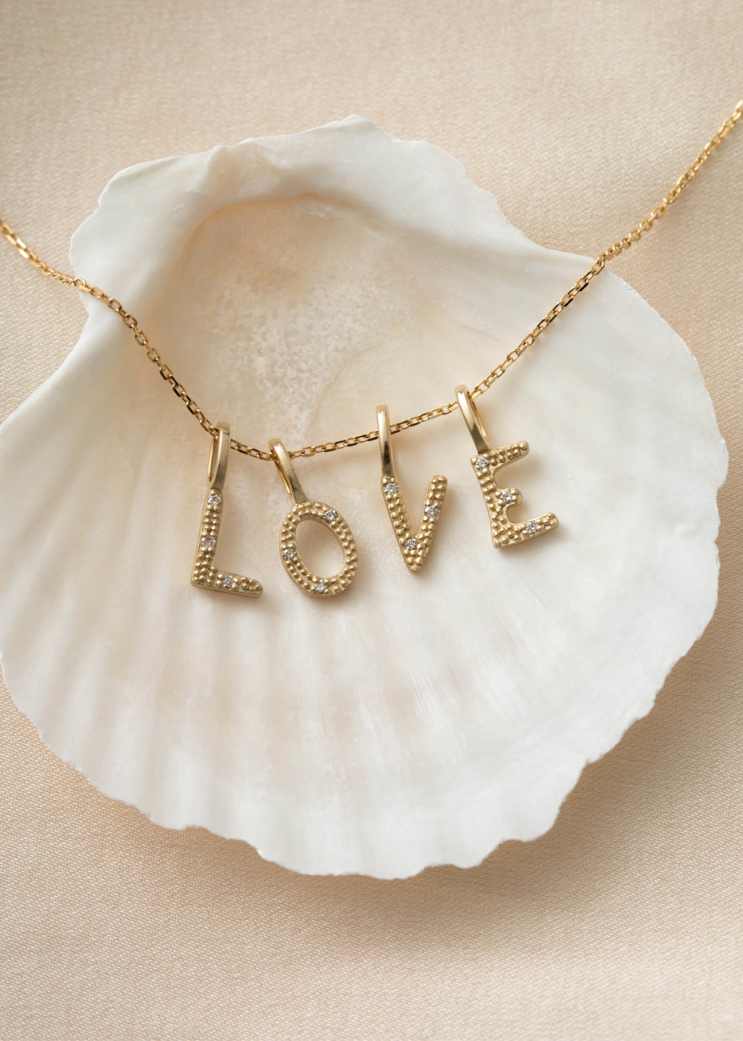 Bogstavsvedhæng i ægte 10 karat guld fra carré jewellery med diamanter, der staver LOVE 