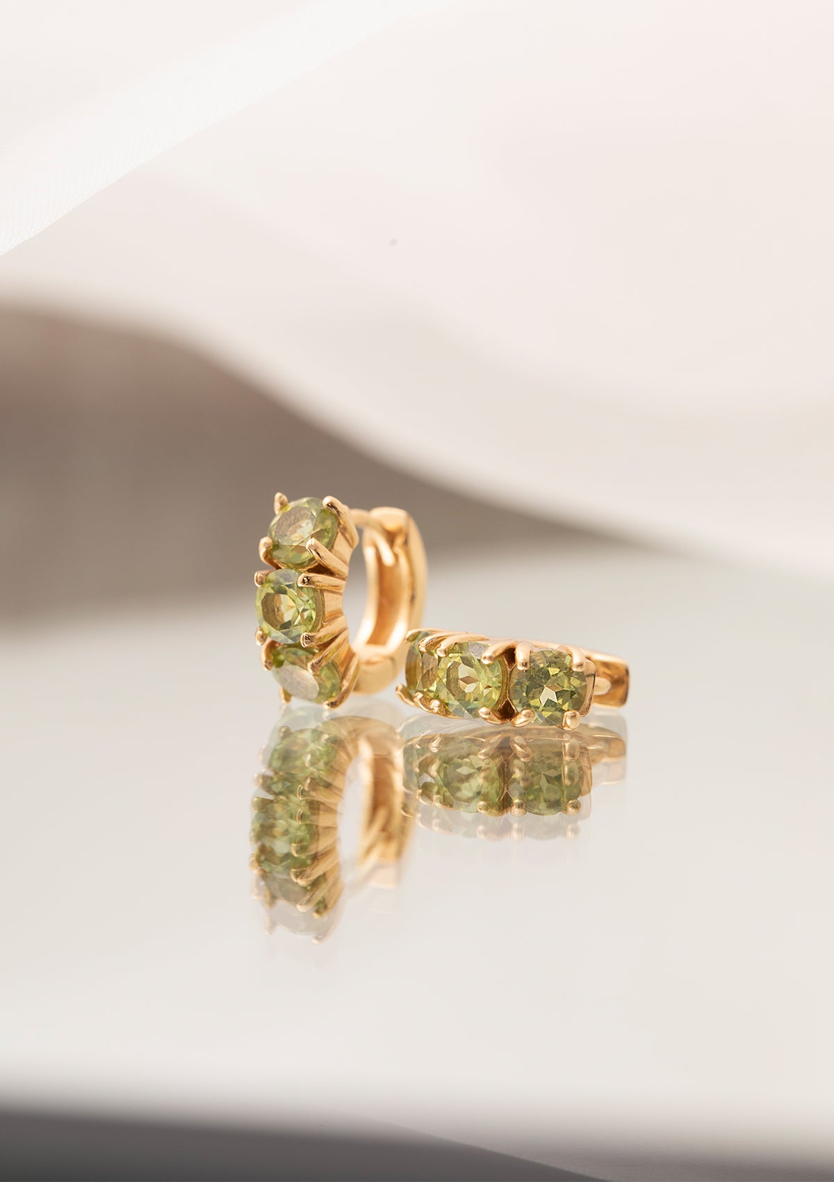 Guldbelagte hoops i creol stil med grønne sten fra Carré. De grønne sten er peridoter