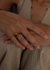 kvinde med guldbelagte ringe fra carré. To tynde og feminine ringe og en ring med store brune sten.