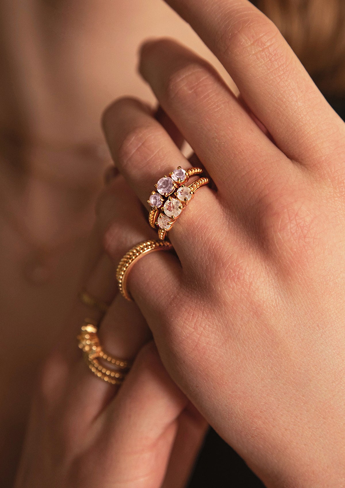 En kvinde med guldbelagte ringe fra Carré. Ringene er valentine ringe og sat med tre store ædelsten i rosa kvarts og månesten