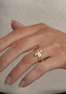 Kvindehånd med to guld smykker i 10 karat guld fra carré. Ringene har en pink turmalin og en grøn turmalin