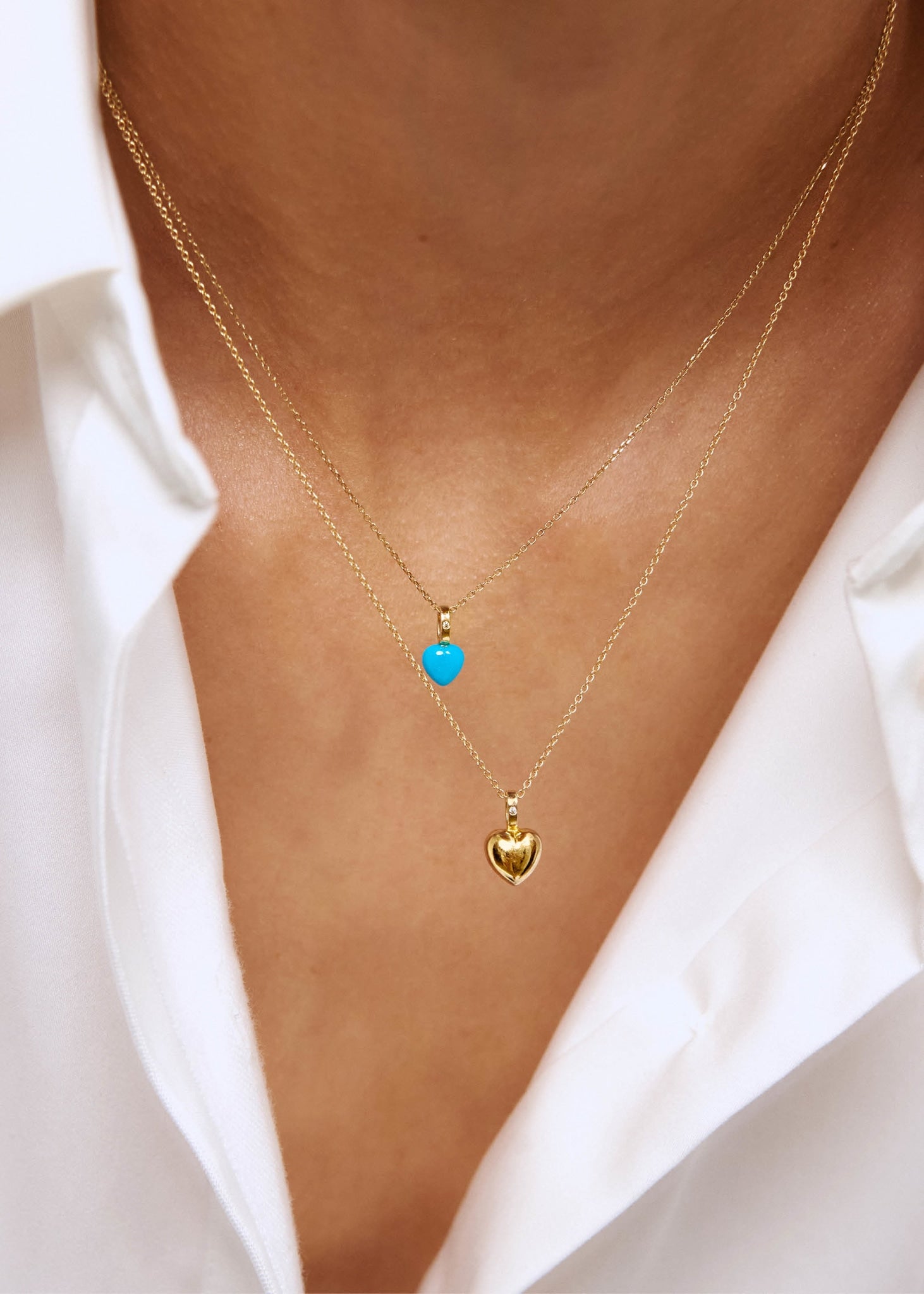 Kvinde med to guld hjerte vedhæng fra carré jewellery i 10 karat guld med en lille diamant og en hjerteformet turkis ædelsten
